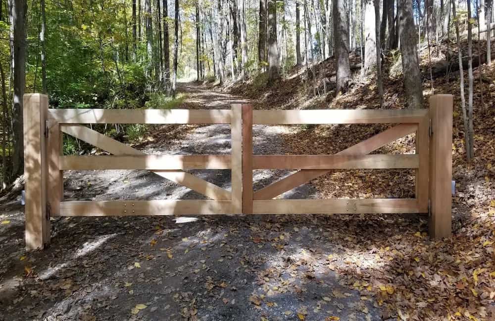 Wooden gate surrounded by tall trees with autumn foliage.