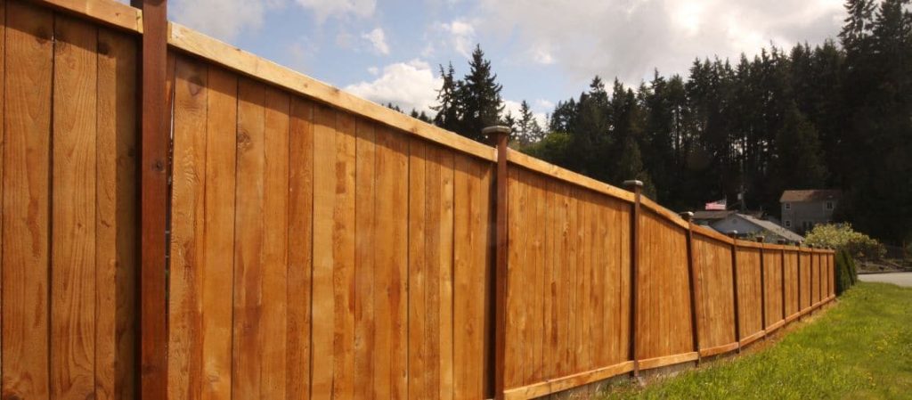 A long wooden privacy fence stretching along a grassy slope