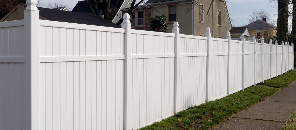A long white vinyl privacy fence with decorative post caps
