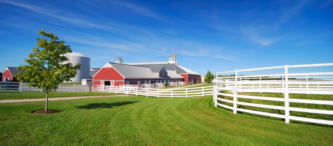 a modern red horse barn with white fences
