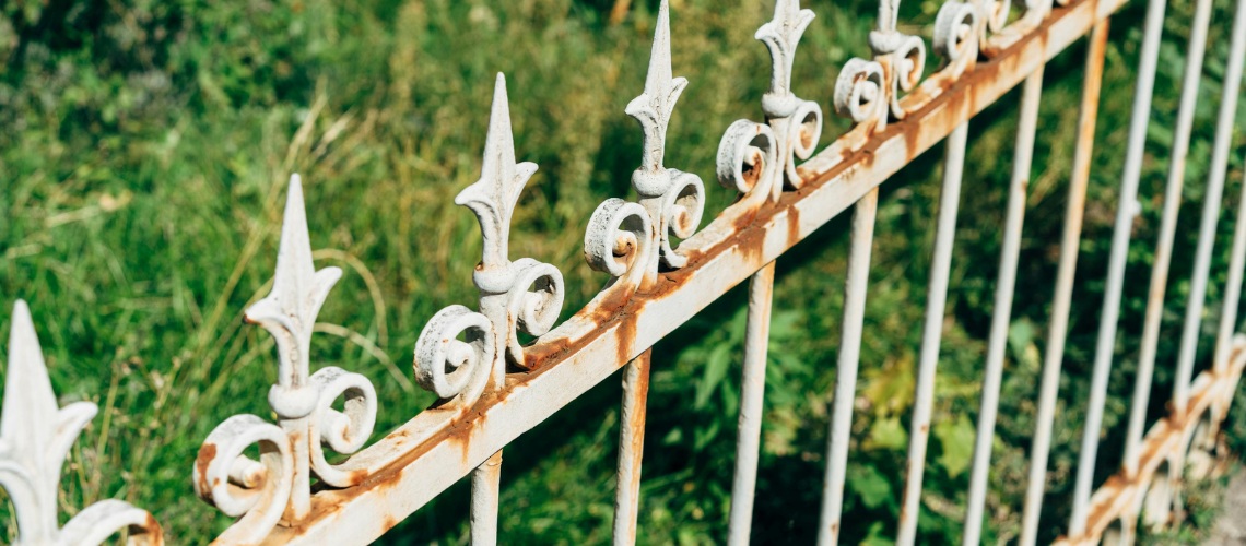 old, rusty white wrought iron fence