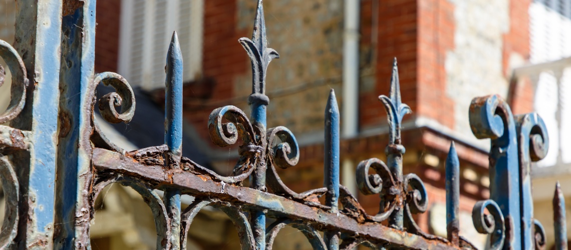 An old, rusty blue wrought iron fence